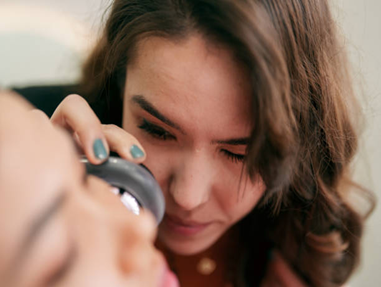 Picture12 | Dr Swetha Cosmodermcentre Close-up of a caregiver helping someone with eye care, using a tool near the other person's eye.